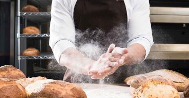 An image of a person holding a tray of freshly baked cookies with the text overlay of "Guide to the Most Searched for Baking Questions: Get expert answers to your baking dilemmas and create delicious treats every time.